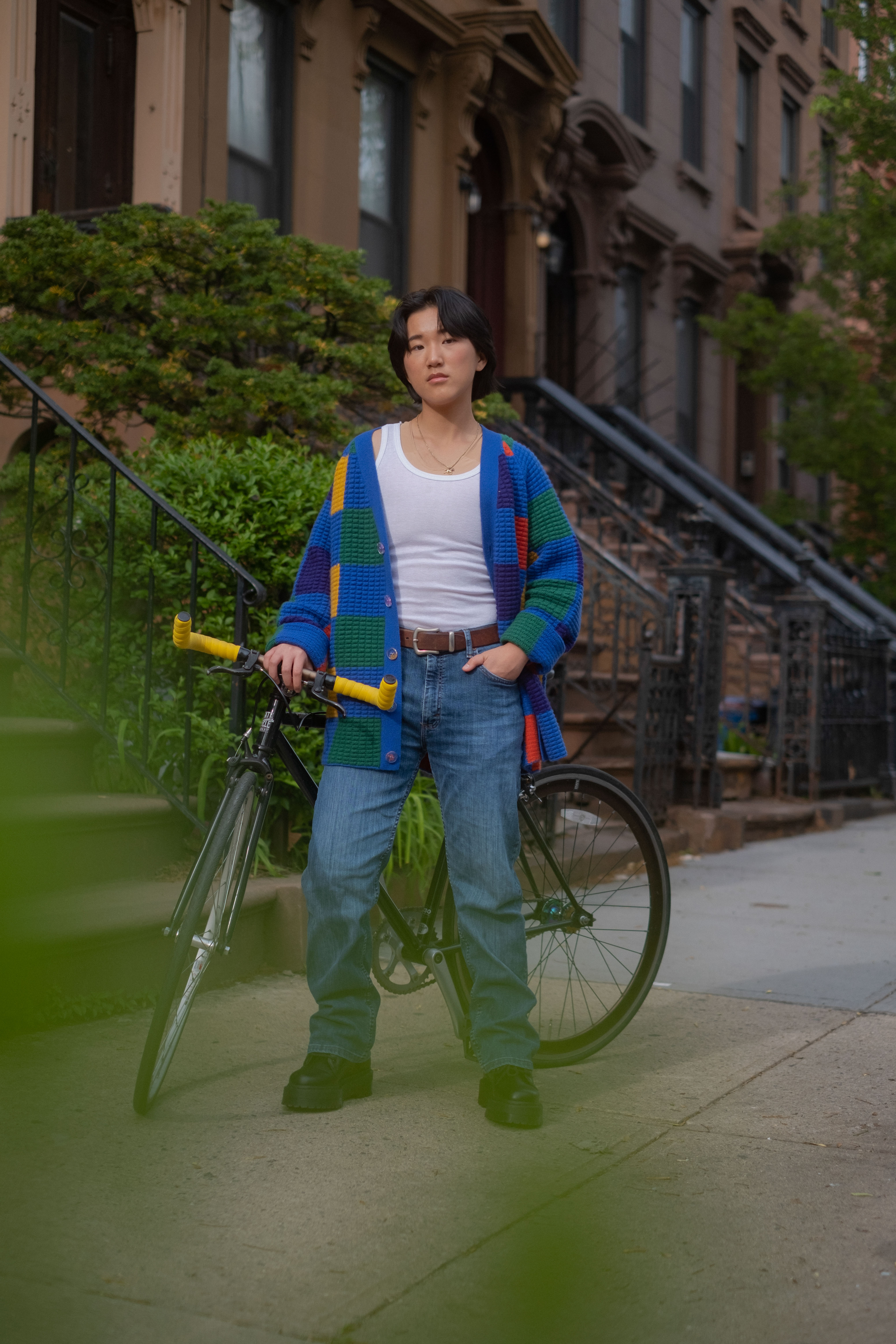 A non-binary trans man standing outside with a bicycle